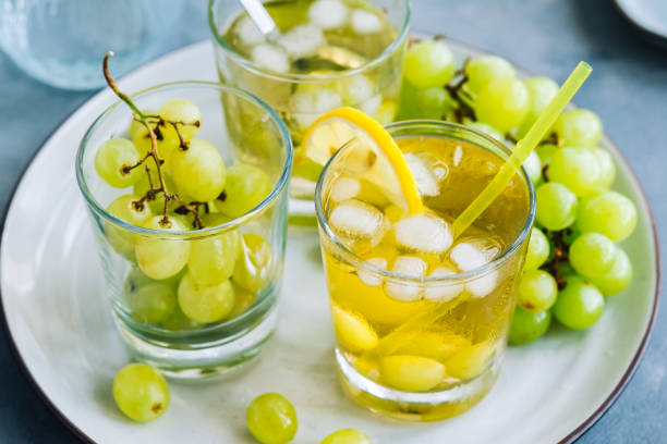 istock Refreshing summer drink in glass with ice cubes, green grape and lemon on the table. 1334101034