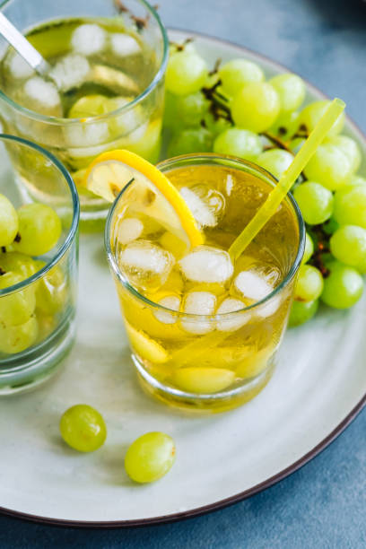 istock Refreshing summer drink in glass with ice cubes, green grape and lemon on the table. 1334101153