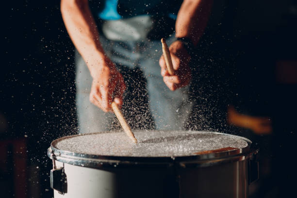 Drum sticks drumming beat rhythm on drum surface with splash water drops Close up drum sticks drumming hit beat rhythm on drum surface with splash water drops percussion instrument stock pictures, royalty-free photos & images
