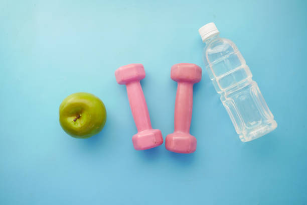 istock fresh drinking water, apple and a pink color dumbbell on table 1334102337