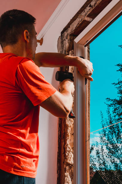 istock Window installation, a new plastic window in a private house, the master uses a rubber hammer to install the window. 1334103371