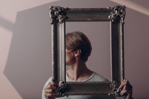 istock Portrait young man standing with picture frame at studio. 1334103966