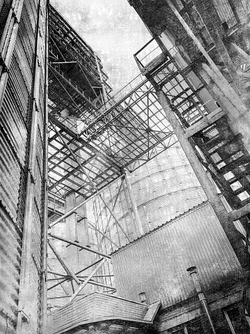 Modern grain terminal is being built on the construction site. A complex of metal structures for storing various crops in front of the sky. View from below upwards. Monochrome. Digital painting