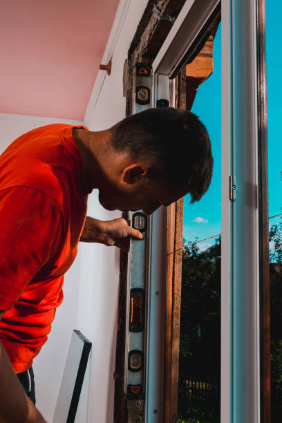 istock The locksmith-installer after fixing the window checks whether it is fixed to the wall, the installation of the window, the master uses the level. 1334105033