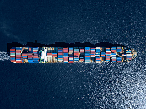 View from above of a fully loaded container ship in the blue sea