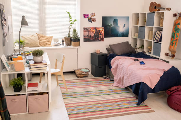 przestronna sypialnia nastoletniego studenta z łóżkiem, biurkiem z lampą i laptopem i innymi rzeczami - poster bed zdjęcia i obrazy z banku zdjęć