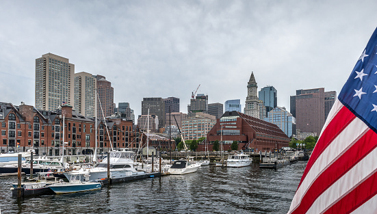 Boston, MA, USA - August 4, 2021: Overcast day to view Boston skyline from a ferry heading to a multi-island tour in Boston Bay. The MBTA boat system comprises several ferry routes.