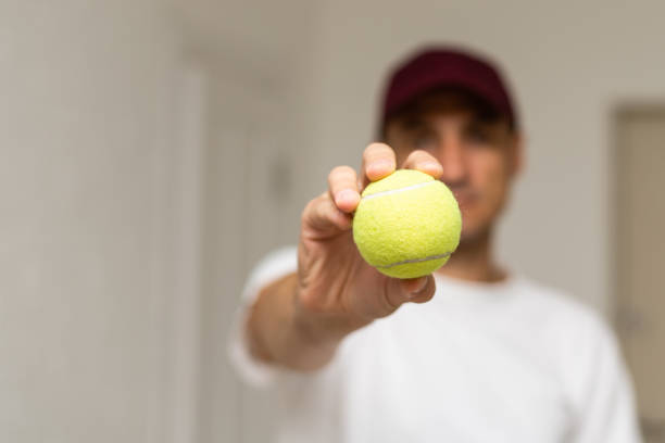 close-up de mão masculina segurando bola de tênis e raquete. tenista profissional começando. - tennis court indoors net - fotografias e filmes do acervo