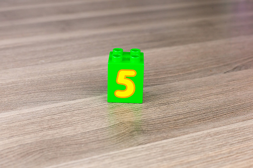 Number five on alphabet blocks displayed on an orange background