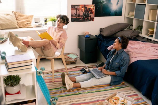 istock Two teenagers reading book and using laptop in bedroom 1334127444