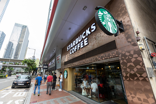 Hong Kong - August 13, 2021 : People walk past the Starbucks Coffee in Hong Kong. Starbucks Corporation is an international coffee and coffeehouse chain.