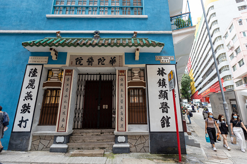 Hong Kong - August 13, 2021 : People walk past the Blue House in Stone Nullah Lane, Wan Chai, Hong Kong. It is one of the few remaining examples of tong lau of the balcony type in Hong Kong. The building was subsequently used as a Dit Da clinic.