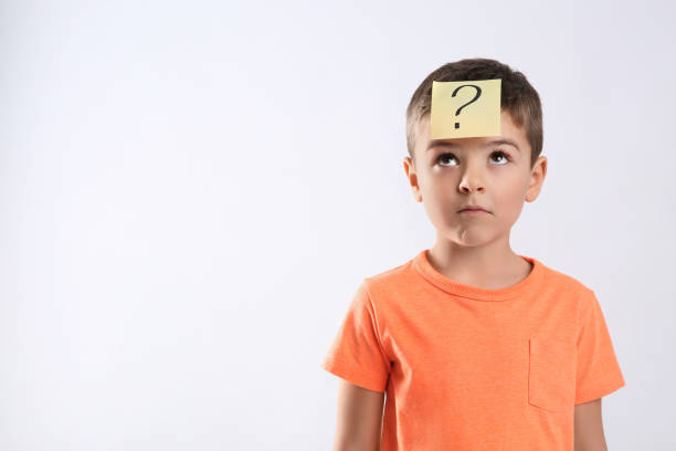 istock Emotional little boy with question mark on white background 1334131641