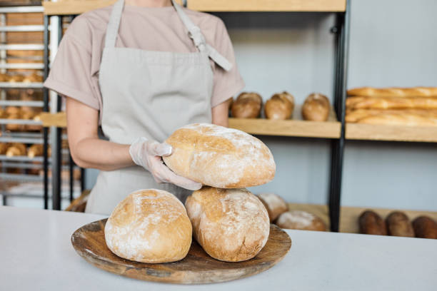 istock Young gloved baker holding fresh baked loaf of bread 1334131920