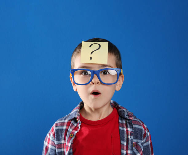 istock Emotional little boy with question mark on blue background 1334131983