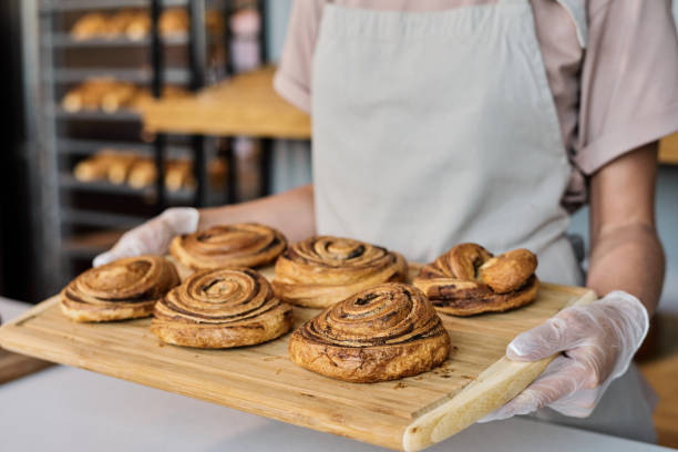 istock Gloved female baker carrying tray with fresh buns 1334132499