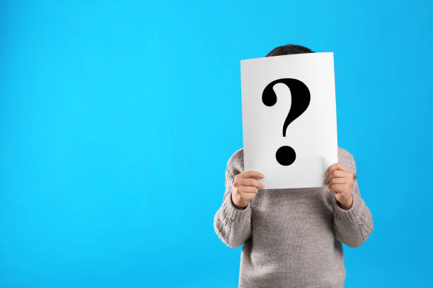 istock Little boy holding paper with question mark on light blue background, space for text 1334132506