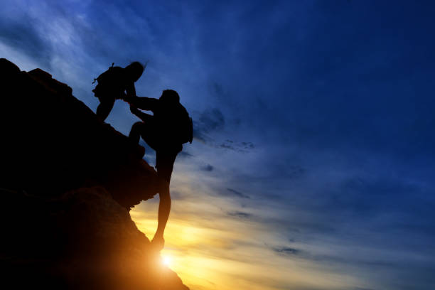 silhouette de l’équipe d’escalade s’aidant les uns les autres tout en grimpant dans un coucher de soleil. le concept d’aide. - insurance lifeguard life sport photos et images de collection