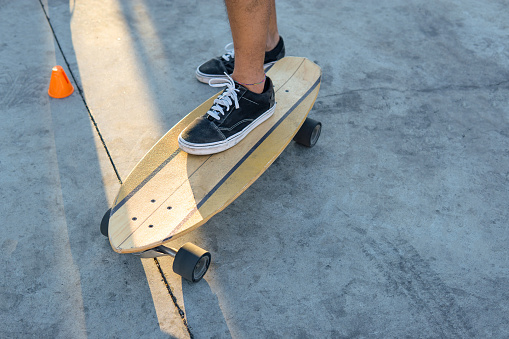 Close up top view young man leg on surf skate or skate board in outdoor. Extream sport