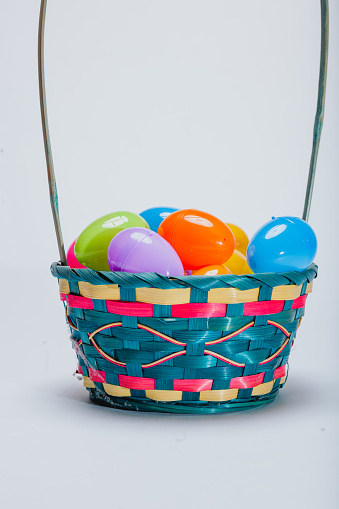 Studio shot of colorful easter eggs around a easter basket. Shot on a white background with copy space.