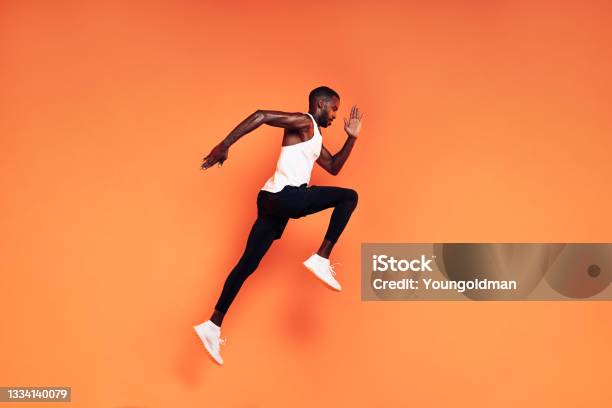 Male Runner Doing Fitness Workout Athlete Exercising Over An Orange Background Stock Photo - Download Image Now