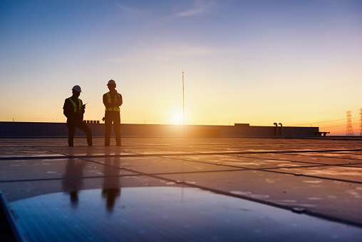 Technician Team checking Photovoltaic cells panels on factory roof, Maintenance of the solar panels, Engineer service, Inspecor concept. Silhouette Photo.