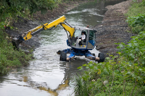 Excavator loader at river with raised bucket over blue skyExcavator loader at river with raised bucket