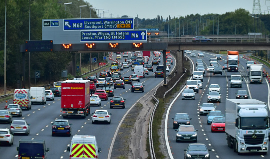 Heavy south bound traffic slows down even further on the M6 Motorway in Lancashire England because of  road works disrupting  the flow of traffic, as motorists approach the junction with the M62 leading off to the Cities  of Liverpool and Manchester, and the M57 heading to Southport .The M6 motorway carries an enormous amount of traffic  heading down from Cumbria in the north to Birmingham in the midlands and beyond.