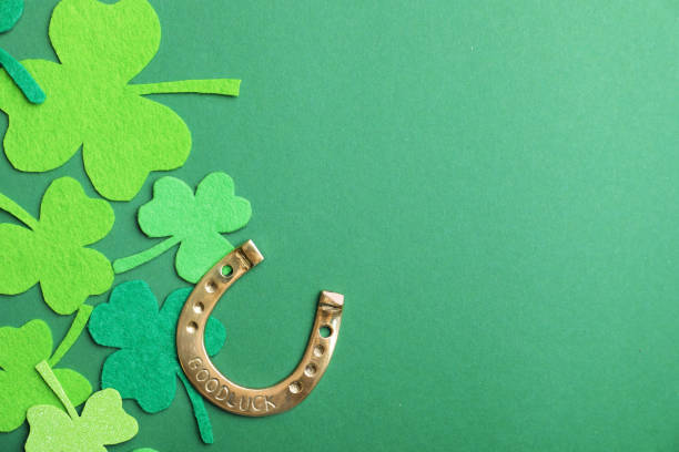 Flat lay composition with clover leaves and horseshoe on green background, space for text. St. Patrick's day
