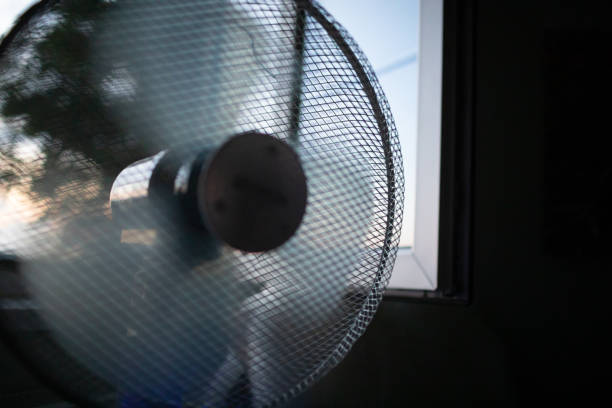 Cooling fan in the light hot summer night by the open window.