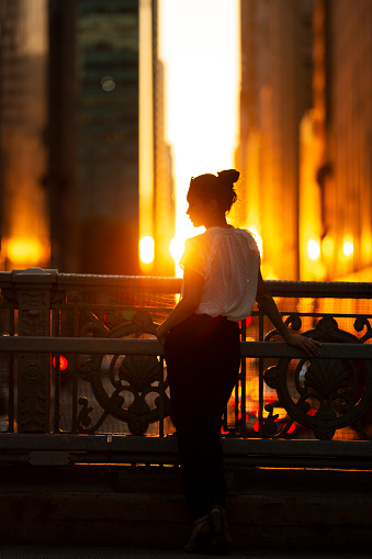 Woman standing at overpass during sunset in midtown Manhattan.
