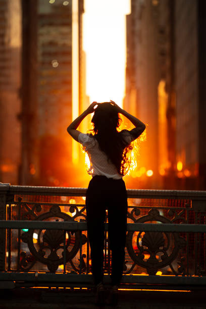 Woman standing at overpass looking at sunset in midtown Manhattan.