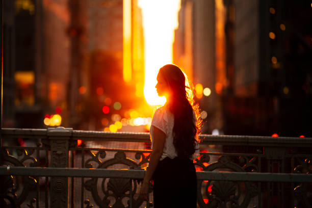 Woman standing at overpass during sunset in midtown Manhattan.