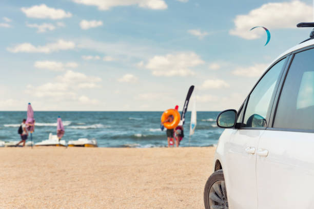 vue latérale de la grande voiture de van suv blanc familiale garée au pittoresque camping de bord de mer de sable côte de mer ou d’océan avec un ciel bleu vibrant sur le fond. location de véhicule voyage voyage de vacances concept de voyage de vacan - nature travel locations photos et images de collection