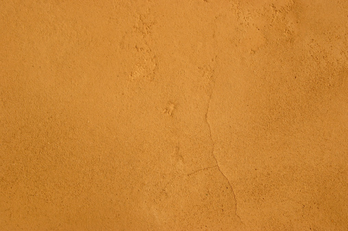 Typicall Mediterranean clay plaster surface, adobe sandy texture with tiny hair cracks.