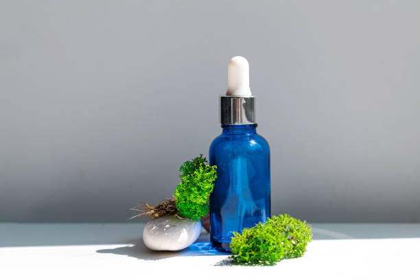 Sea moss personal care. Blue bottle with oil dropper and sea stones and moss on white background. Ingredient for skincare stock photo