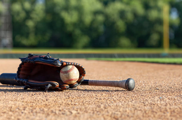 béisbol en un guante con un bate negro de ángulo bajo vista de enfoque selectivo en un campo de béisbol - baseball glove baseball baseballs old fashioned fotografías e imágenes de stock