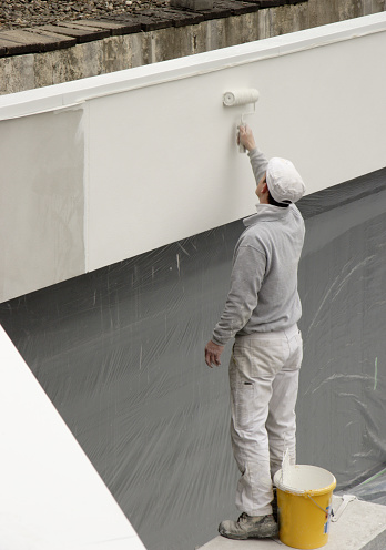 Painter rolling paint on facade