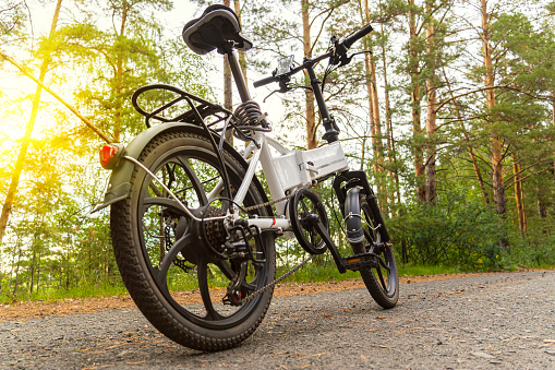 electric bike on an asphalt track in the forest without people. The concept of healthy walking and riding outdoors in the park. Bicycle on the background of a pine summer forest.