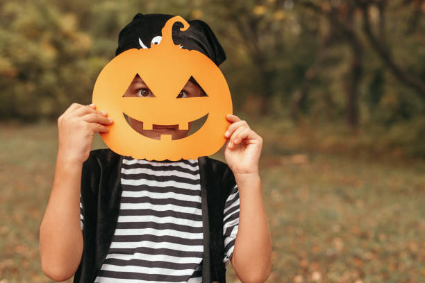 istock Funny kid standing with Halloween mask on nature background 1334184943