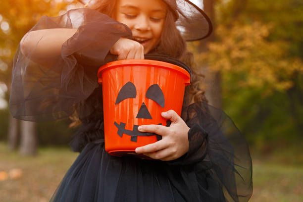 istock Cheerful witch examining trick or treat bucket 1334184965