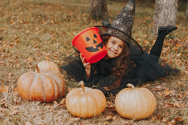 istock Cute girl with pumpkins and empty candy collector 1334184970