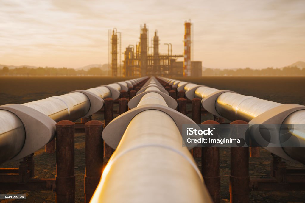 Oil Refinery And Pipeline In Desert During Sunset Steel oil pipes from refinery in desert during sunset. Natural Gas Stock Photo