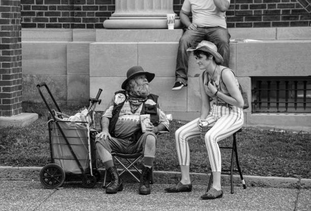 Macedonia, Arkansas, United States  June 27, 2024: Horizontal shot of two old friends sitting outside on the steps of an old country store.