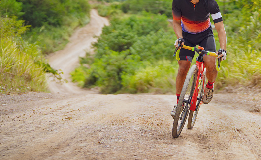 Asian man cycling on gravel road.he is climbing