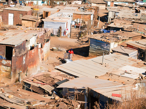 Soweto South Africa, August 15 2007; Shanty town living and homes of some of words poorest people struggling to exist with woman in mid image doing washing outdoors.