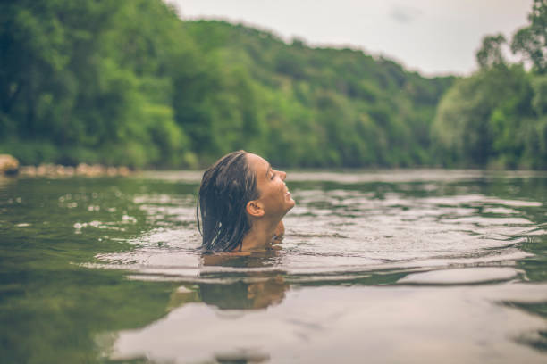 junge frau schwimmt im sommer das seeufer hinunter - wildpflanze stock-fotos und bilder