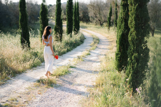 istock Young woman walks down country road, in summer 1334197721