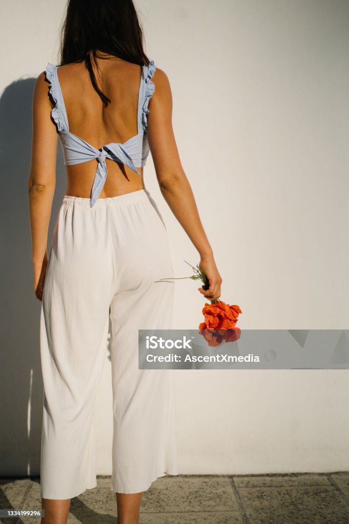 View of young woman holding Flanders Poppies She stands outside home at sunrise, in summertime Crop Top Stock Photo