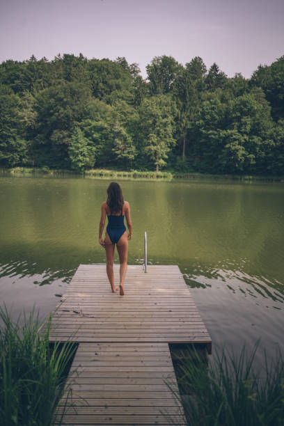 istock Young woman walks down dock near lakeshore 1334201361